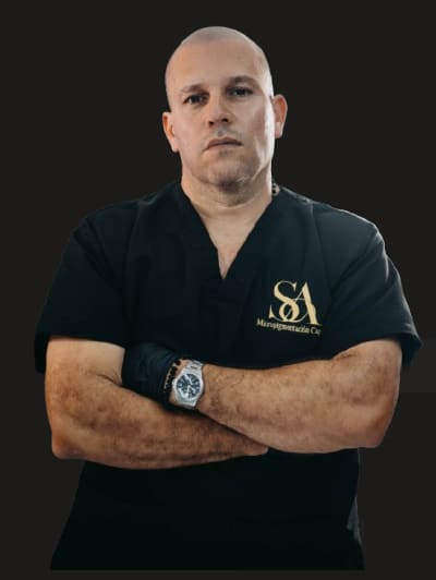 Santiago Abril, especialista en micropigmentación capilar, de brazos cruzados con la camisa negra del estudio y el monograma SA